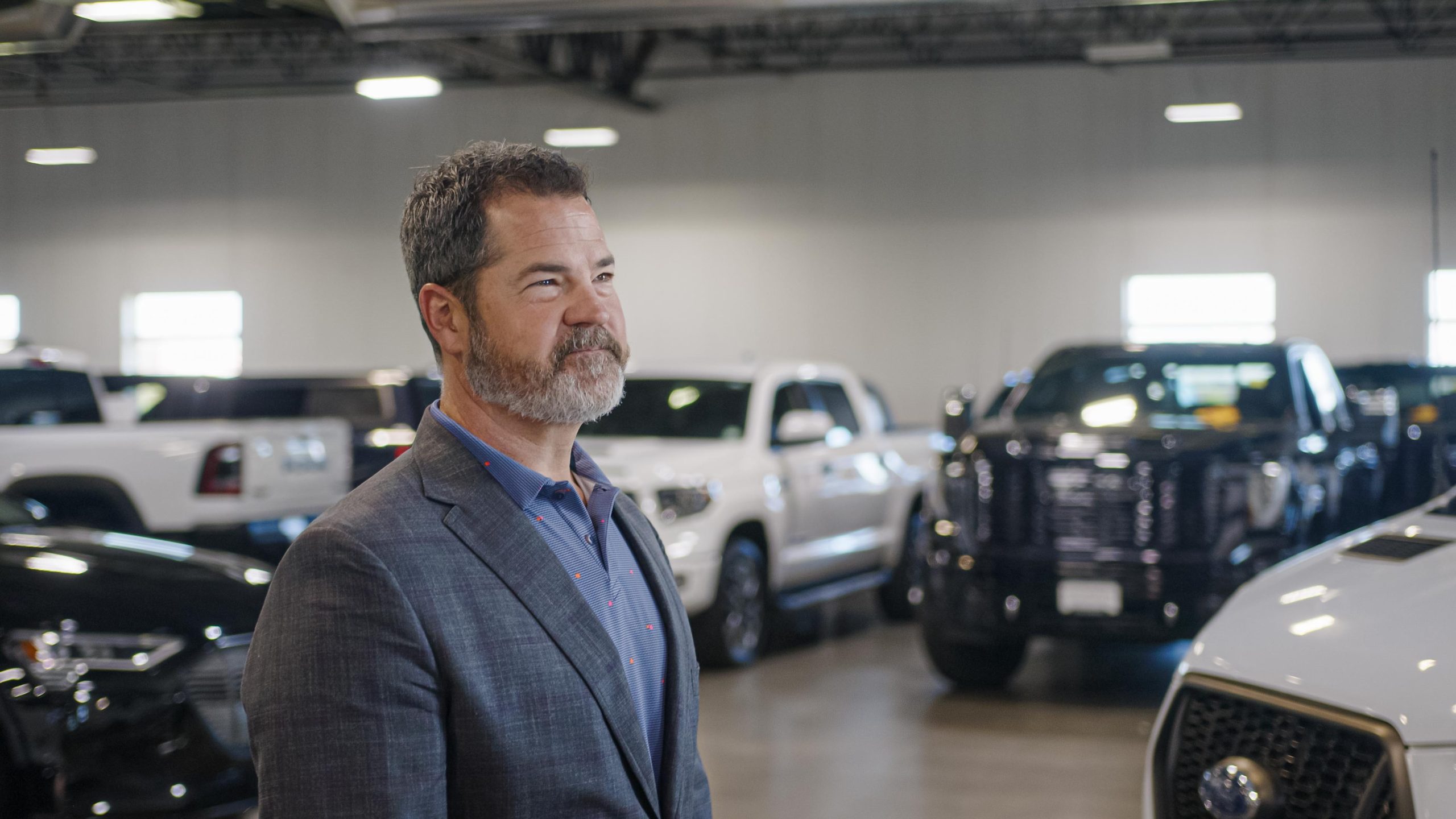 Smiling auto broker standing in front of pick up trucks